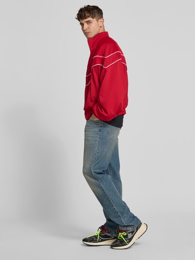 Männermodel trägt Sneaker mit Kontrastbesatz von Dsquared2, abgerundete Form, Schnürverschluss, Ziernähte, strukturierte Sohle, Ganzkörperansicht Rückansicht.