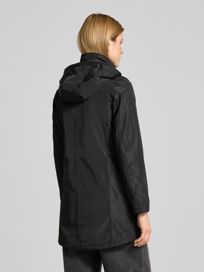 Frauenmodel trägt Regular Fit Mantel mit Logo-Applikation von NAUTGÅRD in Schwarz mit Kapuze und Eingrifftaschen, Ganzkörperansicht Rückansicht. Rückenlänge 88 cm, Schulterbreite 37 cm, Brustweite 48 cm, Ärmellänge 63 cm bei Größe S, Stehkragen mit Logo-Detail, Kapuze mit Tunnelzug.