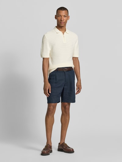 Męski model nosi Regular Fit Poloshirt mit kurzem Reißverschluss od MCNEAL, mieszanka bawełny i wiskozy, fakturowany wzór, kołnierzyk polo, krótki zamek błyskawiczny, długość tyłu 69 cm, długość rękawów 26 cm, widok całej sylwetki z przodu.