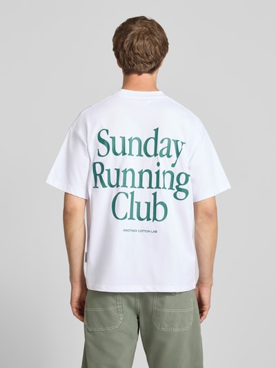 Męski model nosi T-Shirt mit Print und Rundhalsausschnitt von ANOTHER COTTON LAB, bawełna, krój relaxed fit, długość tyłu 69 cm, widok całej sylwetki od tyłu.