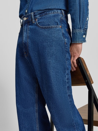 Männermodel trägt Straight Fit Jeans im 5-Pocket-Design von REVIEW, reine Baumwolle, blaue Denim-Struktur, Nahaufnahme Hüfte bis Oberschenkel.