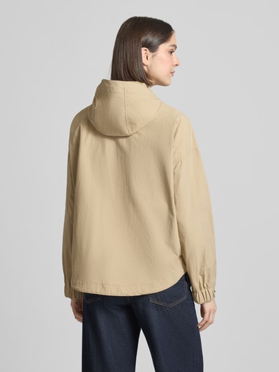 Frauenmodel trägt Jacke mit Kapuze und Zweiwege-Reißverschluss von camel active in Beige, Gerader-Schnitt, strukturierte Oberfläche, Rückenlänge 67 cm, Schulterbreite 44 cm, Brustweite 63 cm, Ärmellänge 62 cm, verstellbare Ärmelabschlüsse, Seitliche Eingrifftaschen, Ganzkörperansicht Rückansicht.