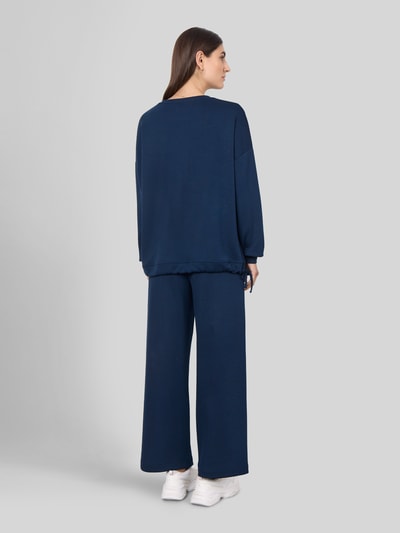 Männermodel trägt spodnie dresowe 'Sweatpants in verkürzter Passform' von Soyaconcept, Mieszanka materiałów z domieszką modalu, prosty krój, jednokolorowy, skrócony fason, elastyczny pas z tunelem, wpuszczane kieszenie, całkowity widok z tyłu.