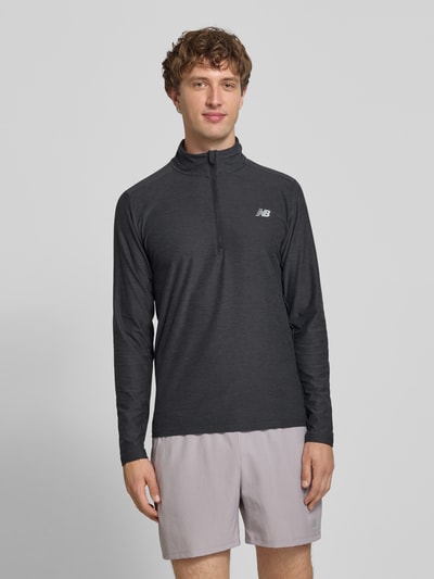 Mężczyznamodel nosi Regular Fit Sweatshirt mit Troyer-Kragen von New Balance, elastyczna mieszanka materiałów, nadruk z logo, Długość tyłu w rozmiarze M: 69 cm, Ganzkörperansicht von vorne.