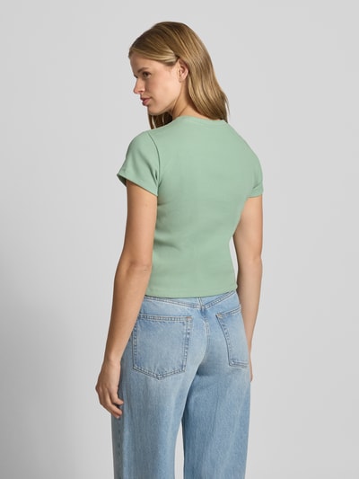 Frauenmodel trägt Cropped T-Shirt in Ripp-Optik mit Logo von Nike aus Baumwoll-Elasthan-Mix in Mint, Rückenlänge 50 cm, Ganzkörperansicht Rückansicht.