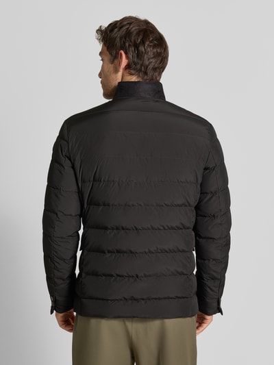 Męski model nosi kurtkę Regular Fit Jacke in Stepp-Optik Modell 'Joen' od Tiger of Sweden, kolor czarny, z efektem pikowania, stójka, kieszenie z patką, listwa guzikowa, krój regular fit, Długość tyłu w rozmiarze 50: 70 cm, Szerokość ramion w rozmiarze 50: 47 cm, Szerokość klatki piersiowej w rozmiarze 50: 51 cm, Długość rękawów w rozmiarze 50: 64 cm, całkowity widok z tyłu