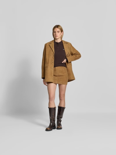 Frauenmodel trägt Blazer aus echtem Ziegenvelours von ROTATE in Camel, Straight Fit, Reverskragen, Pattentaschen, Ganzkörperansicht von vorne.
