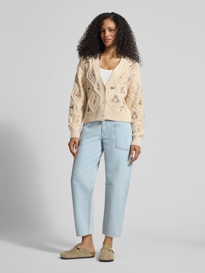 Frauenmodel trägt Strickjacke mit Stitchings von Jake*s Casual in Beige mit V-Ausschnitt, Knopfleiste, sichtbaren Nähten, Ganzkörperansicht von vorne.