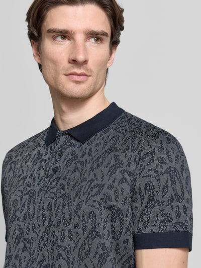 Männermodel trägt Poloshirt mit kurzer Knopfleiste Modell 'Jadson' von JOOP! Collection, meliert in Grau und Dunkelblau, Nahaufnahme Oberkörper.