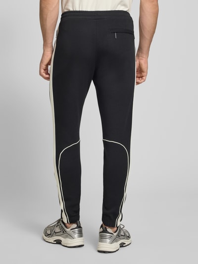 Männermodel trägt schwarzen Slim Fit Tracksuit mit Logo-Stitching Modell 'Egeo' von SERGIO TACCHINI, elastischer Baumwoll-Mix, Ganzkörperansicht Rückansicht.