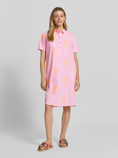 Frauenmodel trägt Knielanges Hemdblusenkleid mit Knopfleiste von Milano Italy aus Baumwoll-Mix, Gerader-Schnitt, Kentkragen, 1/2-Arm, rosa mit orangen Palmen, Ganzkörperansicht von vorne. Rückenlänge 101 cm, Brustweite 45 cm, Ärmellänge 25 cm bei Größe 36.