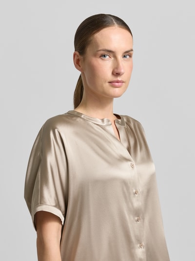 Kobiece modelka ma na sobie Relaxed Fit Seidenbluse mit Rundhalsausschnitt von HERZENS, mieszanka jedwabiu, krótki rękaw, listwa guzikowa, okrągły dekolt, długość tyłu 63 cm, długość rękawów 18 cm, jasny beżowy odcień, połyskująca gładka tekstura, zbliżenie górnej części ciała z przodu.