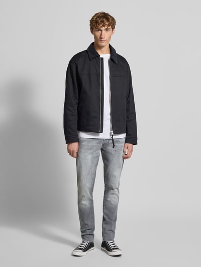 Männermodel trägt Slim Fit Jeans im Used-Look Modell '3301' von G-Star Raw, Baumwoll-Mix mit Stretch-Anteil, Label-Detail, Ganzkörperansicht von vorne.