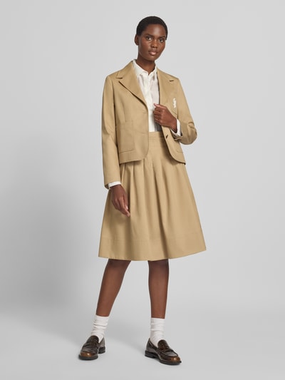 Frauenmodel trägt Knielanger Rock aus reiner Baumwolle von Tommy Hilfiger in Beige mit glatter Textur, Ganzkörperansicht von vorne.