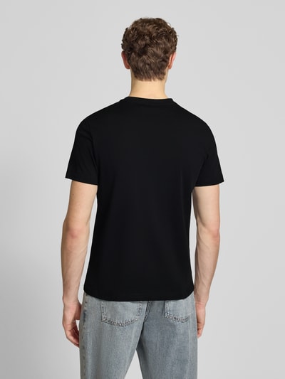 Männermodel trägt T-Shirt mit Label-Print von Antony Morato in Schwarz, gerade geschnitten, zu Jeans, Ganzkörperansicht Rückansicht.