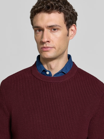 Männermodel trägt Regular Fit Strickpullover aus reiner Baumwolle von MCNEAL, Rundhalsausschnitt, bordeaux, Nahaufnahme Oberkörper.