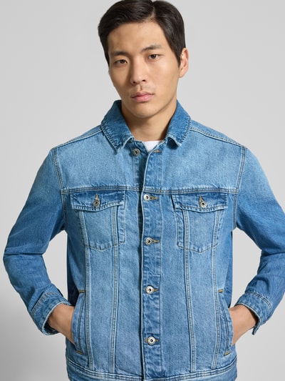 Męski model nosi Jeansjacke mit Brusttaschen von MCNEAL, bawełna, krój regular fit, jasnoniebieski, guziki, długość tyłu 62 cm, szerokość w rozmiarze M 48 cm, szerokość klatki piersiowej 27 cm, długość rękawa 64 cm, widok na górną część ciała z przodu.