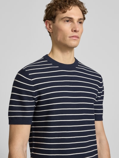 Männermodel trägt Strickshirt mit geripptem Rundhalsausschnitt von MCNEAL in Dunkelblau mit weißen Streifen, reine gewachste Baumwolle, Nahaufnahme Oberkörper.