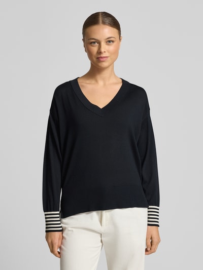 Frauenmodel trägt Regular Fit Pullover aus reinem Lyocell in strickowej optyce od Marella, dekolt w serek, elastyczne i szerokie wykończenia, ozdobne guziki, długość tyłu 57 cm, długość rękawów 53 cm, czarny kolor, imitacja dzianiny, całkowity widok z przodu.