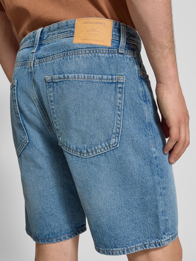 Männermodel trägt Loose Fit Jeansshorts mit Eingrifftaschen Modell 'TONY' von Jack & Jones aus reiner Baumwolle im Used-Look, Ganzkörperansicht Rückansicht.