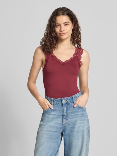 Frauenmodel trägt bordeauxrotes Slim Fit Tanktop aus Viskose-Mix Modell 'BARBERA' von PIECES, feine Spitze, glatte Textur, Nahaufnahme Oberkörper.