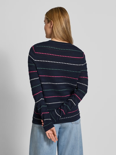 Frauenmodel trägt Cardigan aus reiner Baumwolle von Christian Berg Woman, dunkelblau mit Streifen, eng anliegend, Rückenansicht.