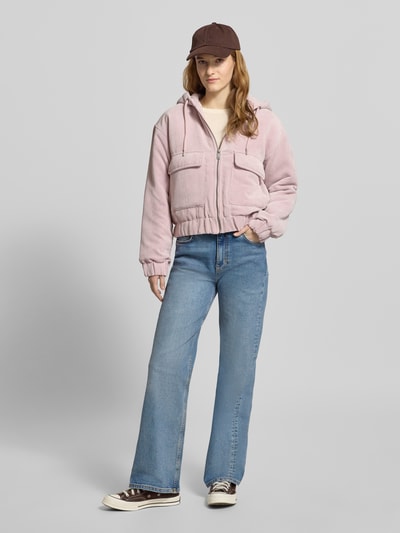 Frauenmodel trägt Regular Fit Bomberjacke mit Kapuze Modell 'SUVA' von ONLY aus Cord, Optik: unifarben, aufgesetzte Vordertaschen, Label-Stitching, gestreiftes Muster, elastischer Ärmel- und Rumpfabschluss, Reißverschluss, Ganzkörperansicht von vorne.