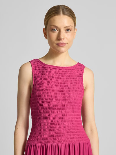 Frauenmodel trägt Midikleid aus Mesh mit Smok-Details von Christian Berg Woman Selection in Pink, strukturierte Oberfläche, Nahaufnahme Oberkörper.