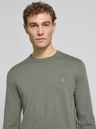 Männermodel trägt Regular Fit Strickpullover aus Baumwoll-Kaschmir-Mix Modell 'KANOVANO_S' von BOSS Orange in unifarbener Optik, Nahaufnahme Oberkörper.