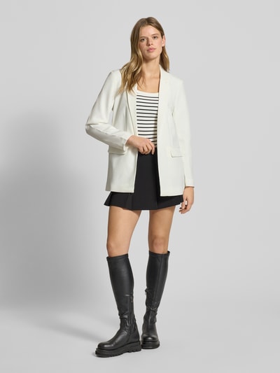 Kobieta modelka nosi Loose Fit Longblazer mit Abnähern Model 'BOZZY' od Pieces, efekt: jednolity kolor, kołnierz z połami, wyhaftowane logo, bez zapięcia, długi rękaw, kieszenie z patką, całość z przodu, pełny widok sylwetki.