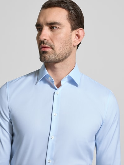 Männermodel trägt Super Slim Fit Business-Hemd mit Kentkragen und Strukturmuster von OLYMP aus Baumwoll-Elasthan-Mix, Nahaufnahme Oberkörper.