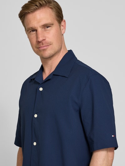 Männermodel trägt Relaxed Fit Freizeithemd aus Seersucker-Material von Tommy Hilfiger, Optik:Allover-Muster, Kurzarm, Nahaufnahme Oberkörper.