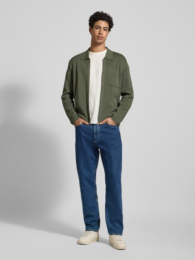Männermodel trägt Tapered-Fit Jeans aus reiner Baumwolle Modell 'RUNNA' von Marc O'Polo Denim, blaue Denim-Optik, Ganzkörperansicht von vorne.