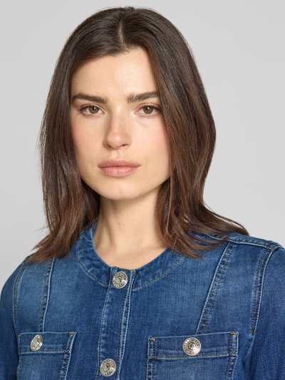 Modelka kobieca nosi Jeansjacke mit Rundhalsausschnitt od Liu Jo White, intensywnie niebieski dżins, bawełna z domieszką stretchu, kieszenie na piersi, krój slim fit, guzik, detalowe przeszycia, szerokość w rozmiarze 36: 45 cm, długość tyłu: 48 cm, szerokość ramion: 37 cm, długość rękawa: 62 cm; zbliżenie na górną część torsu