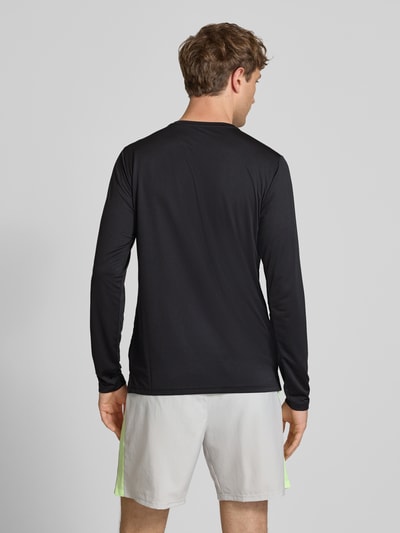 Männermodel trägt Funktionsshirt mit Rundhalsausschnitt und Logo von New Balance, schwarz, Regular-Fit, Longsleeve, Rückenlänge 72 cm bei Größe M, Ganzkörperansicht Rückansicht.