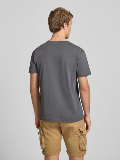 Männermodel trägt T-Shirt mit Logo und Rundhalsausschnitt von Alpha Industries, Baumwolle, Regular Fit, einfarbig grau, Ganzkörperansicht Rückansicht.