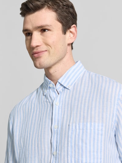 Männermodel trägt Modern Fit Freizeithemd aus reinen Leinen Modell 'Daniel' von Brax, hellblau-weiße Streifen, Button-Down-Kragen, Nahaufnahme Oberkörper.