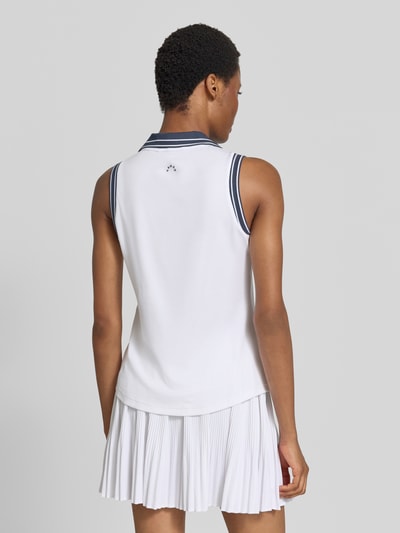 Frauenmodel trägt Regular Fit koszulka polo aus elastischer mieszanka lyocellu Modell 'Isaac' von VARLEY, kołnierzyk polo, krój bez rękawów, długość tyłu w rozmiarze S: 61 cm, biała z granatowymi akcentami, gładka faktura, Ganzkörperansicht Rückansicht.