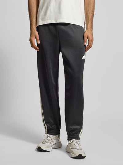 Männermodel trägt Sweatpants mit elastischem Bund von adidas Sportswear, Baumwoll-Anteil, Lockerer-Schnitt, Label-Print, Eingrifftaschen, Ganzkörperansicht von vorne.