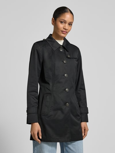 Frauenmodel trägt Trenchcoat mit Ärmelriegeln von Fuchs Schmitt in Schwarz, glatte Textur, Umlegekragen, Regular Fit, Nahaufnahme Oberkörper.