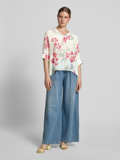 Frauenmodel trägt Relaxed Fit Bluse aus Viskose-Mix im Allover-Look von Comma mit V-Ausschnitt, 3/4-Arm, Knopfleiste, florales Muster in Rosa und Hellblau, und verlängertem Rückenteil, Ganzkörperansicht von vorne.