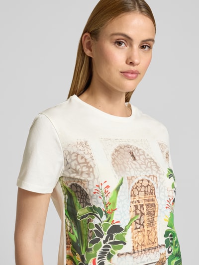 Modelka kobieca nosi Regular Fit T-Shirt mit Allover-Motiv-Print od Marc Cain z bawełny, okrągły dekolt, motyw roślinny, rozmiar 36, krótki rękaw, kolorowe liście i motywy, perspektywa: zbliżenie na górną część ciała