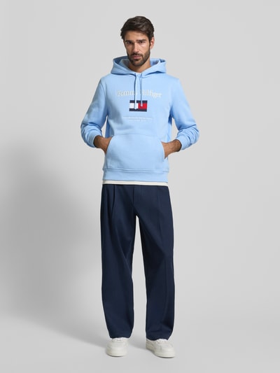 Męski model nosi Regular Fit Hoodie aus Baumwoll-Mix od Tommy Hilfiger, niebieski, z kapturem, kieszenią kangurką, przód na całej sylwetce.