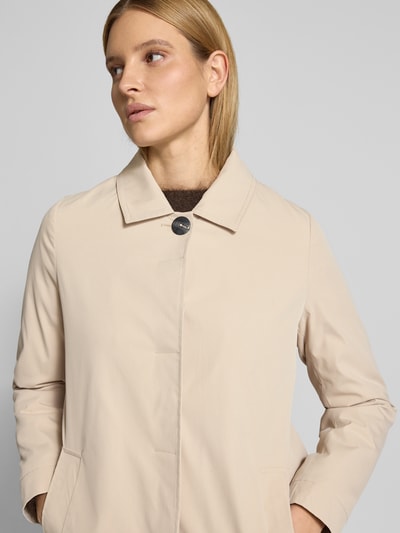 Frauenmodel trägt Mantel mit verdeckter Knopfleiste und Eingrifftaschen von Christian Berg Woman Selection in Beige, Nahaufnahme Oberkörper, Gerader-Schnitt, Kentkragen, Rückenlänge 87 cm, Schulterbreite 40 cm, Brustweite 54 cm, Ärmellänge 62 cm.