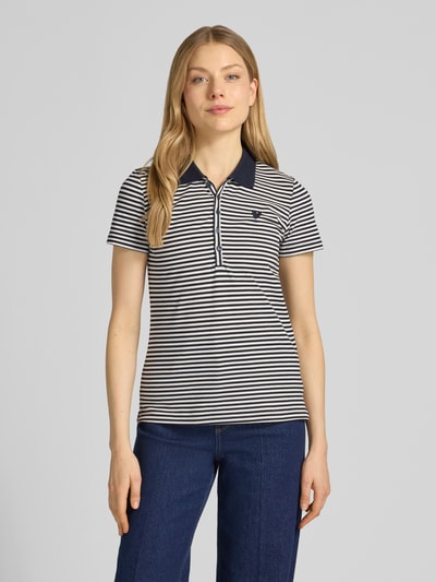 Frauenmodel trägt Regular Fit Poloshirt aus Baumwoll-Mix von Tom Tailor, efekt: wzór w paski na całej powierzchni, kołnierzyk polo, dekolt w serek, krótki rękaw, mieszanka bawełny, wyhaftowany motyw, pikowana faktura, kolor granatowo-biały, krój regular fit, listwa guzikowa, Ganzkörperansicht von vorne