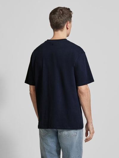 Männermodel trägt unifarbenes, dunkelblaues Relaxed Fit T-Shirt aus Bio-Baumwoll-Mix Modell 'MAARKOS' von Armedangels, Ganzkörperansicht Rückansicht.
