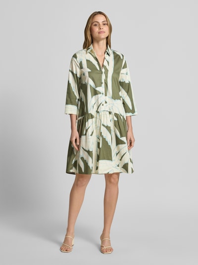 Kobiece model prezentuje knielanges Hemdblusenkleid mit Eingrifftaschen von Christian Berg Woman, zielony wzór na całej powierzchni, bawełna, linia a, długość do kolan, listwa guzikowa, wpuszczane kieszenie, długość tyłu w rozmiarze 36: 100 cm, szerokość w rozmiarze 36: 45 cm, długość rękawów w rozmiarze 36: 48 cm, całkowity widok z przodu.