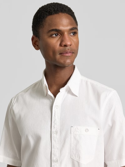 Männermodel trägt Regular Fit T-Shirt aus Baumwoll-Mix von Lerros in Weiß mit Rundhalsausschnitt und Label-Detail, Nahaufnahme Oberkörper.