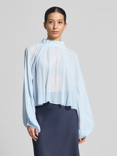 Frauenmodel trägt Loose Fit Langarmbluse aus reiner Viskose Modell 'AFFETTO' von MAX&Co., Optik: Unifarben, Relaxed-Fit, Stehkragen, einreihige Knopfleiste, Raglan-Ballonärmel mit schmaler Manschette, Materialverarbeitung: Crépon, Farbe Hellblau, leichte transparente Textur, Ganzkörperansicht von vorne.