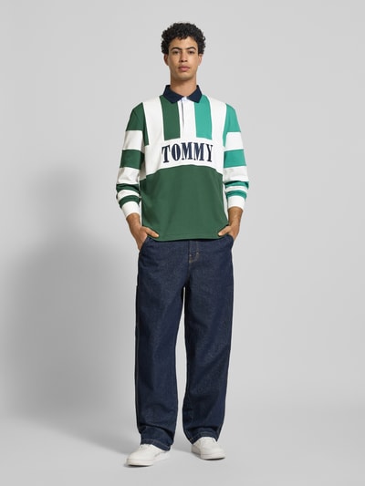 Männermodel trägt Relaxed Fit Poloshirt aus reiner Baumwolle von Tommy Jeans, Optik: Unifarben, mehrfarbig, Ganzkörperansicht von vorne.